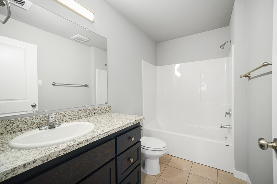A beautiful bathroom with grey walls, white trim, granite countertops, and tile flooring