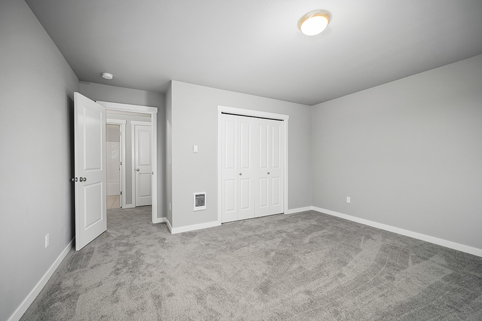 A beautiful open room with grey walls, white trim, and grey carpet