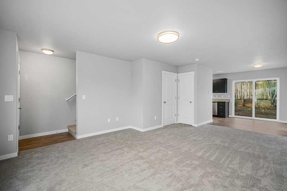 A beautiful open room with grey walls, white trim, and grey carpet