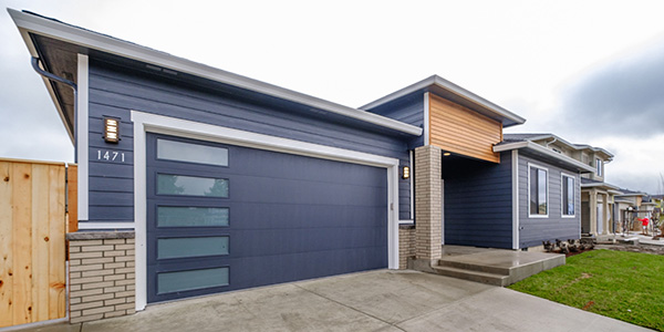 the front of a newly built home with navy siding light gray bricks and wood accents