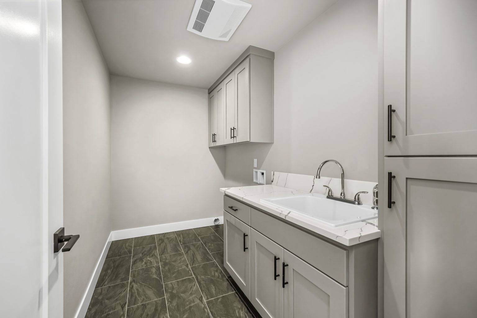 new construction bathroom with light gray cabinets, large white sink with stainless steel faucet